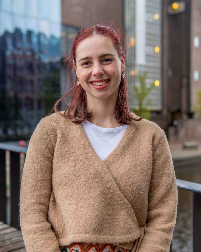Student lachend in de camera met rood haar en beige trui